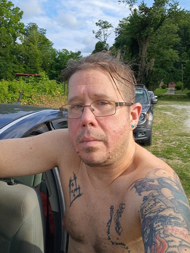 Photo by TheJTLovecraft with the username @TheJTLovecraft, who is a verified user,  July 3, 2024 at 9:18 PM and the text says 'After finishing a  shift at work. #selfie #tattoos #northcarolina'