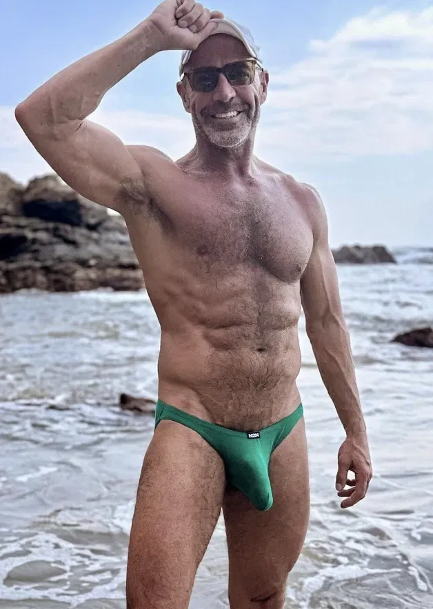 Photo by Nickplus33 with the username @Nickplus33, who is a verified user,  May 2, 2024 at 3:15 AM and the text says '#daddy #muscled #outdoors #beach #hairy #trimmed  #beard #shades #bulge #caps'