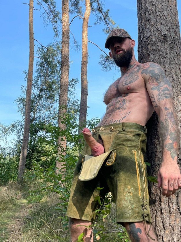 Photo by Nickplus33 with the username @Nickplus33, who is a verified user,  October 15, 2023 at 3:29 AM and the text says '#ink #hung #reveal #beard #lederhosen #outdoors #hairy #ink #uncut #beard'