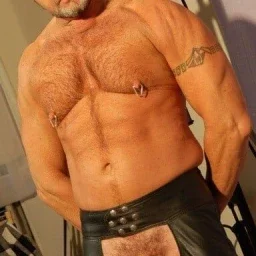 Photo by Nickplus33 with the username @Nickplus33, who is a verified user,  May 10, 2024 at 6:05 AM and the text says '#leather #daddy #beard #hairychest #hairy #cockring #hung #thickdick #chaps'